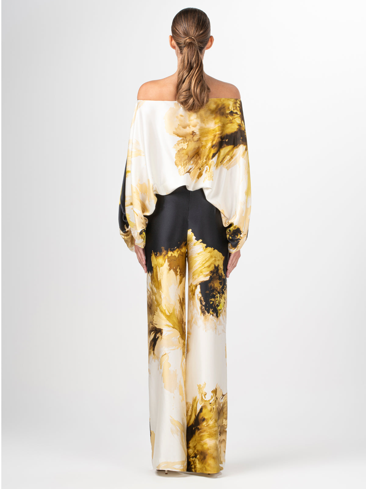 An off-the-shoulder Bellagio Blouse Golden Peony with a black and gold print.