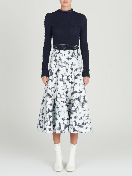 Sentence with product name: A Grettel Skirt White Denim with a black and white print, made of textured denim fabric.