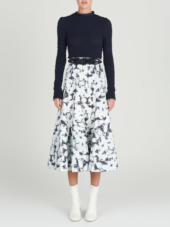 Sentence with product name: A Grettel Skirt White Denim with a black and white print, made of textured denim fabric.