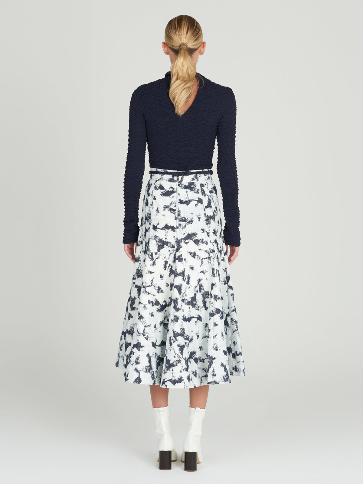 Sentence with product name: A Grettel Skirt White Denim with a black and white print, made of textured denim fabric.