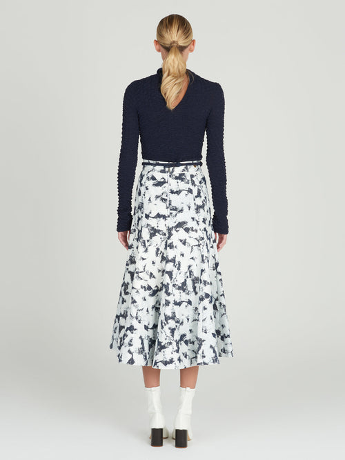 Sentence with product name: A Grettel Skirt White Denim with a black and white print, made of textured denim fabric.